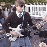 a man playing a guitar and singing into a microphone