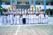a group of students pose for a picture in front of a school
