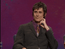 a man in a suit is covering his mouth with his hands