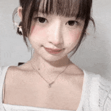 a close up of a girl wearing a necklace and a white top .