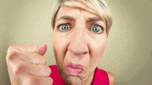 a woman is making a funny face while pointing at the camera .