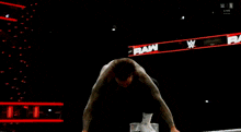 a wrestler is flying through the air while another wrestler is laying on the ground during a wrestling match .