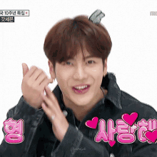 a young man is making a heart shape with his hands and the word love is above him in pink letters