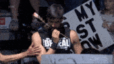 a man in a bf real wrestling club shirt holds a stick