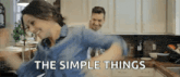 a man and a woman are dancing in a kitchen with the words `` the simple things '' written on the bottom .