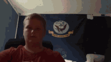 a young man stands in front of a united states navy flag