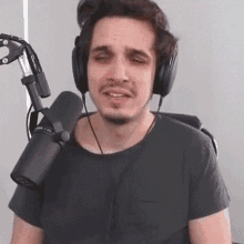 a man wearing headphones and a microphone is sitting in front of a microphone and making a funny face .