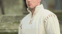 a man wearing a white shirt with brown lace up sleeves
