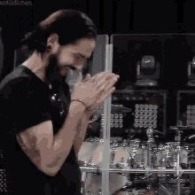 a man with a beard is praying with his hands together in front of a drum set .