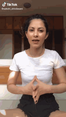 a woman in a white t-shirt and black shorts is making a tiktok