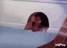 a person is laying in a bathtub with their head sticking out of it .