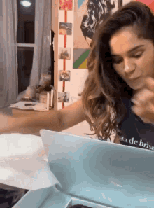 a woman wearing a t-shirt that says ' a de brisa ' on it is using a laptop