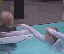 a couple of people are swimming in a pool and one of them is wearing a wet shirt .