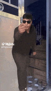 a man wearing sunglasses stands in front of a door