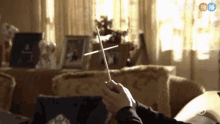 a person is holding a baton in a living room with chinese writing on the bottom
