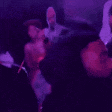 a blurry picture of a group of people dancing in a club with purple lights .