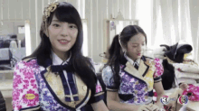 a group of girls are sitting in a room and one of them is wearing a floral dress .