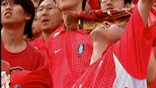 a group of people wearing red nike shirts are watching a sports game
