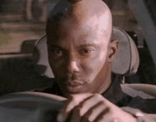 a bald man is sitting in the driver 's seat of his car