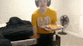 a man wearing a yellow shirt that says 12 % nba champs is holding a tray of food