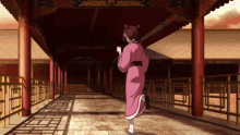 a woman in a pink kimono is walking down a narrow hallway