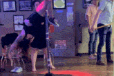 a pole dancer performs in front of a be careful watch your step sign