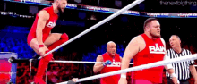 a group of wrestlers are standing in a wrestling ring .