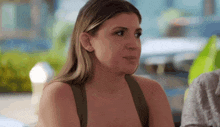 a woman in a green tank top looks at the camera with a serious look on her face .