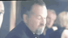 a man with a beard is standing in front of a group of people in a room .