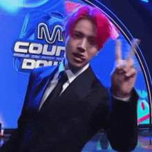a man in a suit and tie is giving a peace sign in front of a m count sign .