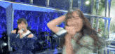a woman is singing into a microphone while another woman looks on .