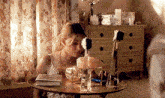 a woman is sitting at a table looking at herself in the mirror .