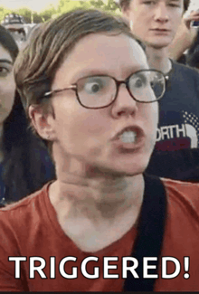 a man wearing glasses and a red shirt with the word triggered on the bottom