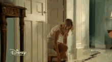 a woman is kneeling in front of a disney channel door