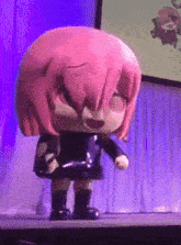 a doll with pink hair is standing on a stage in front of a purple curtain