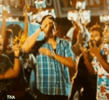 a man in a plaid shirt is dancing in a crowd of people