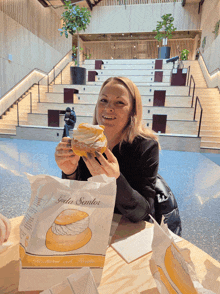 a woman holding a donut next to a bag that says gala sentroi