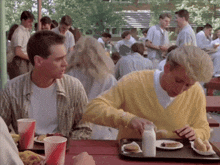 a man in a yellow sweater is pouring milk into a hot dog