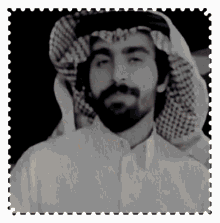 a black and white photo of a man with a beard and scarf