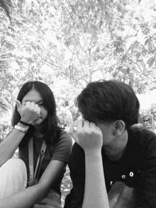 a black and white photo of a boy and a girl with the girl covering her face with her hands
