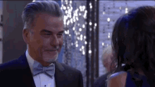 a man in a tuxedo is smiling at a woman in a blue dress .
