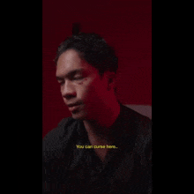 a man in a black shirt is talking to another man in a red room .