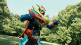 a colorful robot is standing in a field with trees in the background .