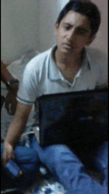 a man in a white shirt is sitting in front of a black laptop