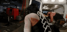 a wrestler is kneeling down in front of an ambulance in a garage .