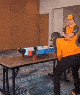 a man wearing an orange shirt with the word mclaren on it is standing next to another man