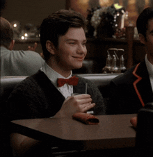 a man in a bow tie is holding a glass of soda