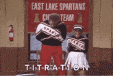 two cheerleaders are standing in front of a sign that says east lake spartans cheer team