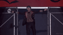 a man stands on a stage with his arms in the air with abema in the corner