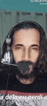 a man with a beard wearing headphones with a microphone in his mouth .